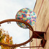 A colourful PU basketball featuring a floral design is shown near a basketball hoop against a blue sky.