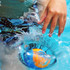 A vibrant orange and blue water bouncing ball partially submerged in a pool with rippling water.