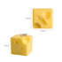 Square cheese-shaped candles in a pale yellow colour, featuring small holes and a wick on top.