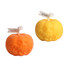 Two pumpkin-shaped candles in orange and yellow, featuring carved faces and topped with white wicks.