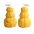 Triple pumpkin-shaped candles in yellow, featuring playful skull designs. Two stacked pumpkins visible.