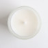 A white glass candle in a frosted container, viewed from above, with a simple design and no visible branding.