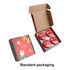 A set of four red tin candles in a festive box with holiday designs and a logo.