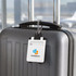 A white ABS luggage tag attached to a grey suitcase, featuring a logo and adjustable strap.