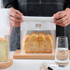 A person holds a clear, resealable bag containing sliced bread. The bag features a logo at the top. A person holds a clear, resealable bag containing sliced bread. The bag features a logo at the top.
