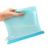 A silicone reusable storage pouch in a translucent light blue with a blue base, held in a hand.