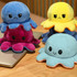 A collection of large reversible octopus plush toys in pink, blue, yellow, and light blue, featuring different facial expressions.