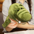 A green crocodile hand puppet with a friendly face and soft texture, held by a person.