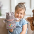 A grey plush rhino hand puppet with a smiling face, held by a child wearing a blue dress and a tiara.