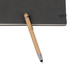 A bamboo pen with a stylus nib rests on a dark notebook, featuring a metal clip and shiny accents. A bamboo pen with a stylus nib rests on a dark notebook, featuring a metal clip and shiny accents.