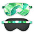 A satin sleep mask featuring a vibrant green leaf pattern on one side and a solid black reverse with a decorative band.