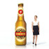 An inflatable beer bottle in brown with a label and a woman in a black skirt and white top beside it.