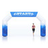 A large inflatable arch in blue and white, featuring a logo, with a runner passing through it.