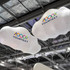Two large white inflatable clouds with a logo, suspended from the ceiling at an exhibition event.