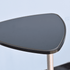 A triangular black tabletop with a smooth finish, mounted on a silver pole. A triangular black tabletop with a smooth finish, mounted on a silver pole.