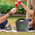 A grey felt cooler bag with a handle and logo, set on a picnic blanket, surrounded by drinks and greenery.