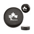 A black hockey puck shape stress reliever featuring a white maple leaf design and a logo.