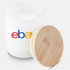 A large white candle in a glass jar with a bamboo lid and a logo on the side.