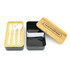 A two-layer lunch box in black and natural wood, featuring white utensils and a compartment divider. It has a logo area.