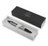 A matte grey ballpoint pen in a black and white presentation box, featuring a logo.