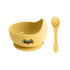 A yellow silicone kids' suction bowl and spoon, featuring a logo, designed for stable feeding.