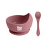 A silicone kids suction bowl in pink with a matching spoon. The bowl features a logo on the front.