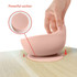 A pink silicone suction bowl with a smooth surface, designed to stick securely to flat surfaces. Features a logo.