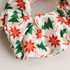 A hair scrunchie featuring a white background with red snowflakes and green Christmas trees in a festive pattern.