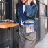 A clear crossbody tote bag with blue accents, featuring a zipper closure and an attached logo. A clear crossbody tote bag with blue accents, featuring a zipper closure and an attached logo.