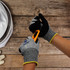Cut resistant nitrile gloves in grey and black with a yellow cuff, being used to handle a utility knife.