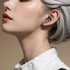 Wireless earbuds in a sleek design, displayed on a model with grey hair, showcasing a modern and stylish appearance.