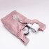 A pink velvet wrist bag containing glasses and a small round container. It has a soft, textured surface.