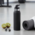A black drink bottle with a silver cap, placed next to a rolled exercise mat and sliced kiwi fruit.