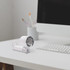 A compact personal cooling fan in white sits on a desk beside a keyboard and a cup with art supplies.