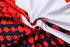 A close-up of a sublimated football jersey featuring a red, white, and black design with circular patterns and a logo.