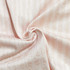 A close-up view of light pink fabric with a textured pattern, showcasing breathable material ideal for garments.