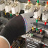 A pair of grey and black insulating gloves reaching towards electrical components in a control panel.