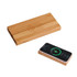 A bamboo wireless power bank in natural wood finish, alongside a smartphone displaying a charging icon.