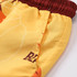 A pair of men's board shorts in yellow with a maroon waistband, featuring a vibrant design and a side pocket.