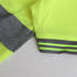 A close-up of a lime green hi-vis reflective polo shirt featuring grey sleeves and striped detailing.