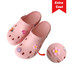 Pink clog slides featuring decorative embellishments and ventilation holes, with a logo present on the side.