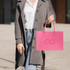 A pink customizable felt tote bag with two handles, held by a person wearing a grey coat and button-down shirt.