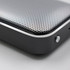 A silver and black Bluetooth speaker with a perforated surface and smooth edges, featuring a small button on the side.