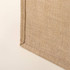A textured beige fabric corner, showcasing a natural woven look with neatly stitched edges.