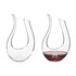 A U-shaped wine decanter made of clear glass, featuring a logo and filled with red wine.