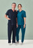 A navy blue and teal women's V-neck scrub top paired with matching pants, presented on a male and female model.