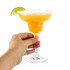 A margarita glass filled with orange drink, garnished with a lime wedge and salt on the rim. Hand holding the glass.