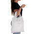 A white reusable shopping bag is held by a person, displaying a simple design and shoulder straps.
