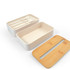 A cream-colored eco lunch box with a bamboo lid and an insert containing utensils.