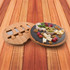 A bamboo cheese board with a slate surface, featuring assorted cheeses, olives, grapes, and walnuts. It includes knife slots.